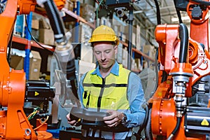Worker man working with robot arm automate welding machine in modern metal factory. Engineer program robotic in heavy industry