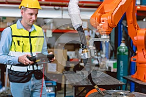 Worker man working with robot arm automate welding machine in modern metal factory. Engineer program robotic in heavy industry