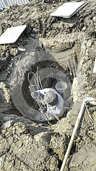 Worker man working in square pit use spade dig big hole for make foundation pile