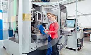 Worker and manager discussing production at a machine tool