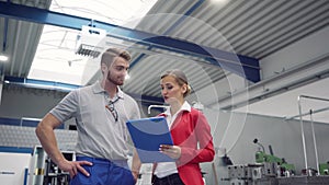 Worker and manager discussing production at a machine tool