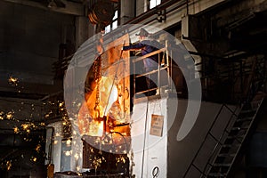 Worker manages molten metal pouring in industrial environment, steel production high-temperature furnace, sparks flying