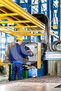 Worker in manufacturing plant at machine control panel