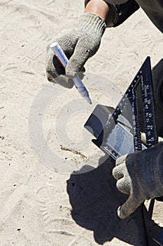 A worker marks the cut line on a piece of metal