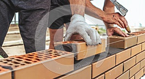 Worker or mason hands laying bricks close up. Bricklayer works at brick row. Brickwork on construction site