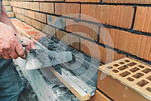 Worker or mason hands laying bricks close up. Bricklayer works at brick row. Brickwork on construction site