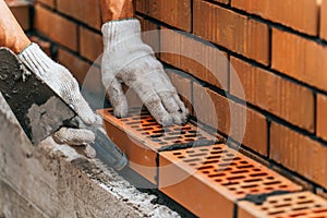 Worker or mason hands laying bricks close up. Bricklayer works at brick row. Brickwork on construction site