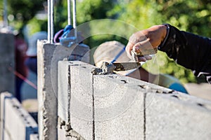 Worker masonry are building walls with cement blocks and mortar