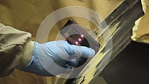 Worker measures a thickness of primer on a car`s body using a thickness gauge 4K