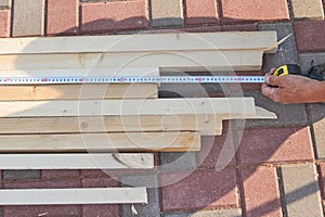 Worker measures wooden beams on the tile floor Construction works