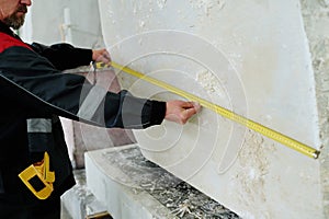 Worker measuring the big piece of stone with ruler