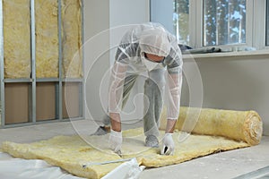 Worker measuring and cutting insulation material indoors