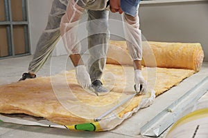 Worker measuring and cutting insulation material indoors