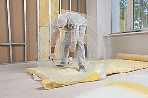 Worker measuring and cutting insulation material indoors