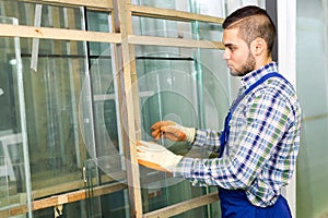 Worker measuring glass at factory