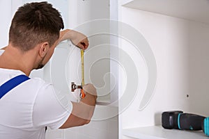 Worker measuring newly installed kitchen furniture
