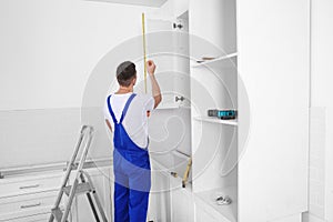 Worker measuring newly installed kitchen furniture