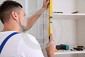 Worker measuring newly installed kitchen furniture