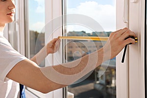 Worker measuring plastic window indoors, closeup. Installation process