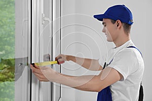 Worker measuring plastic window indoors. Installation process