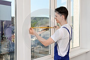 Worker measuring plastic window. Installation process