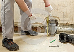 A worker is measuring the sewage drain pipe