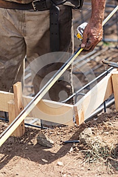 Worker Measuring Steel Rebar At Construction Site