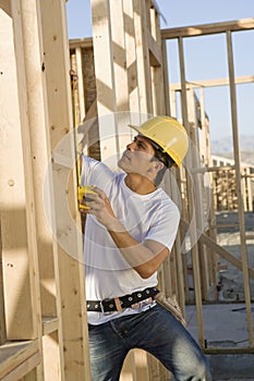 Worker Measuring Timber At Construction Site