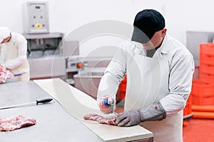 A worker in meat factory, chopped a fresh beef meat on work table, industry of a processing and production food