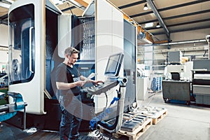 Worker in metal industry operating a modern cnc lathe