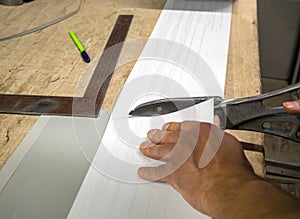 A worker with metal shears cuts a strip of the desired size