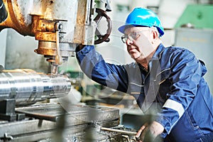 Worker miller operating milling machine at industrial manufacturing factory