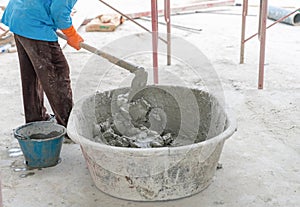 Worker mixing concrete with sparrow in plastic tub