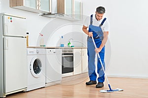 Worker Mopping Floor In Kitchen At Home