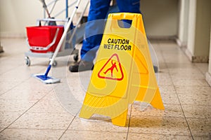 Worker Mopping Floor With Wet Floor Caution Sign photo