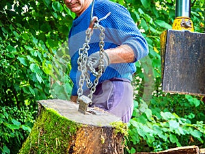 A worker moves a large log to a chain for splitting in a machine.