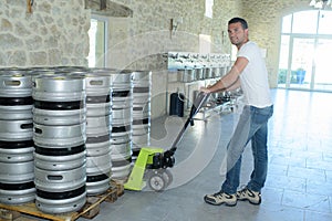 Worker moving barrels with pallet truck