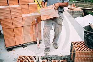 worker moving bricks and using tools for building exterior walls with bricks and mortar