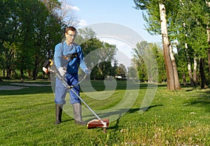 The worker mows the grass using a trimmer image,maintenance the greenery