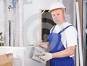 Worker mudding sheetrock wall