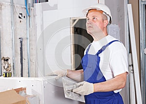 Worker mudding sheetrock wall