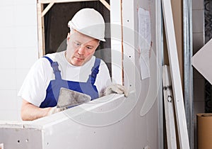 Worker mudding sheetrock wall