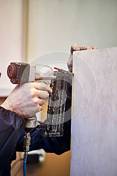 Worker with nailing gun in a workshop