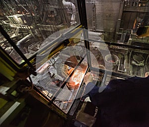 Worker operates in the cabin of a cargo crane at the steel mill