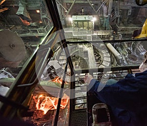 Worker operates in the cabin of a cargo crane at the steel mill
