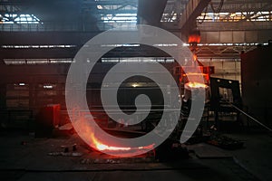 Worker operates metal casting process in metallurgical plant