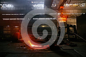 Worker operates metal casting process in metallurgical plant