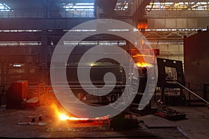 Worker operates metal casting process in metallurgical plant