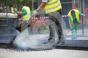 Worker operating asphalt paver machine during road construction