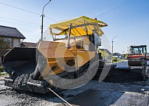 Worker operating asphalt paver machine during road construction and repairing works. A paver finisher, asphalt finisher